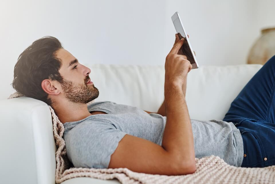 Mężczyzna korzystający z tabletu na kanapie